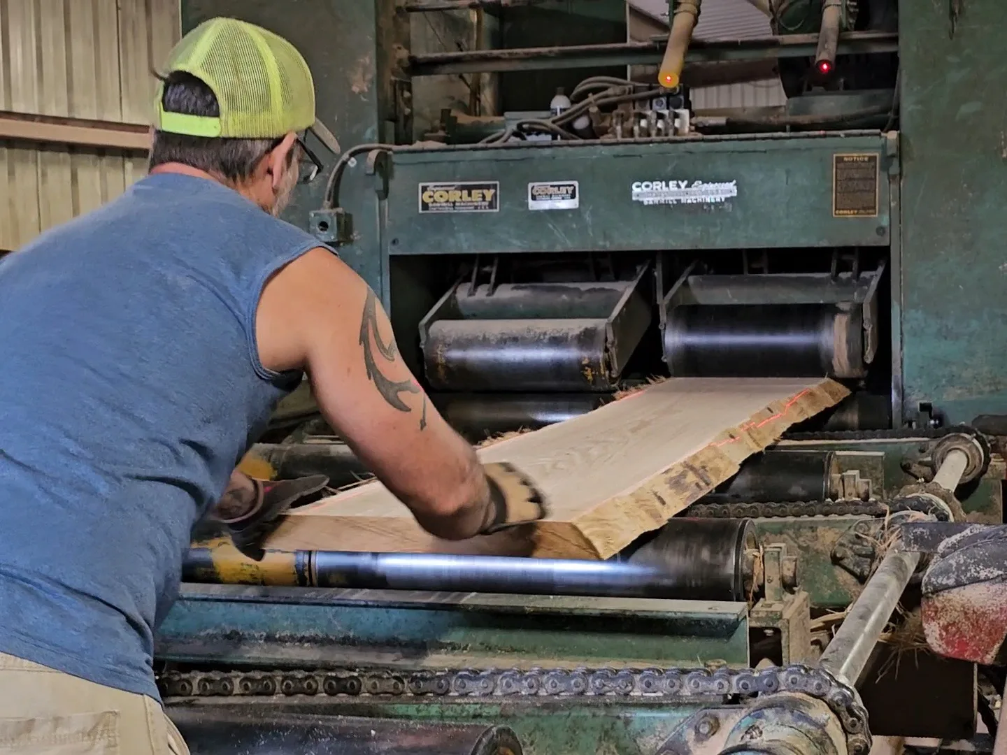 Worker guiding a rough-cut hardwood board through a Corley sawmill at Turman Forest Products in Hillsville, Virginia, showcasing precision lumber processing and sustainable wood manufacturing.