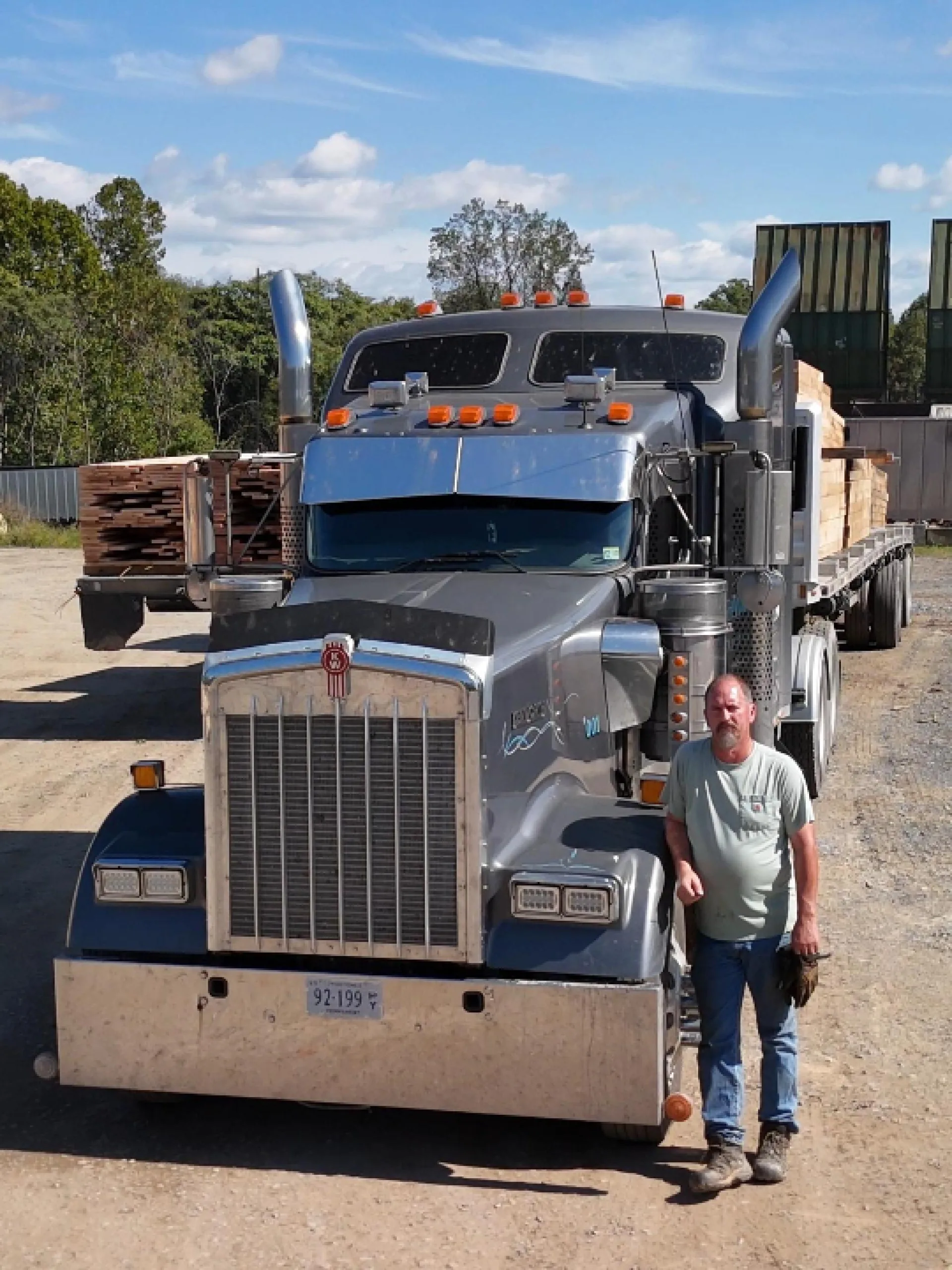 Turman Forest Products driver standing beside a flatbed truck loaded with Appalachian hardwood lumber, showcasing dependable delivery and logistics within The Turman Group’s vertically integrated forestry operations.